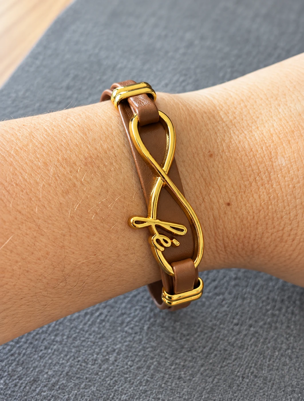 Pulseira marrom com detalhe dourado de fé, apresentada no pulso